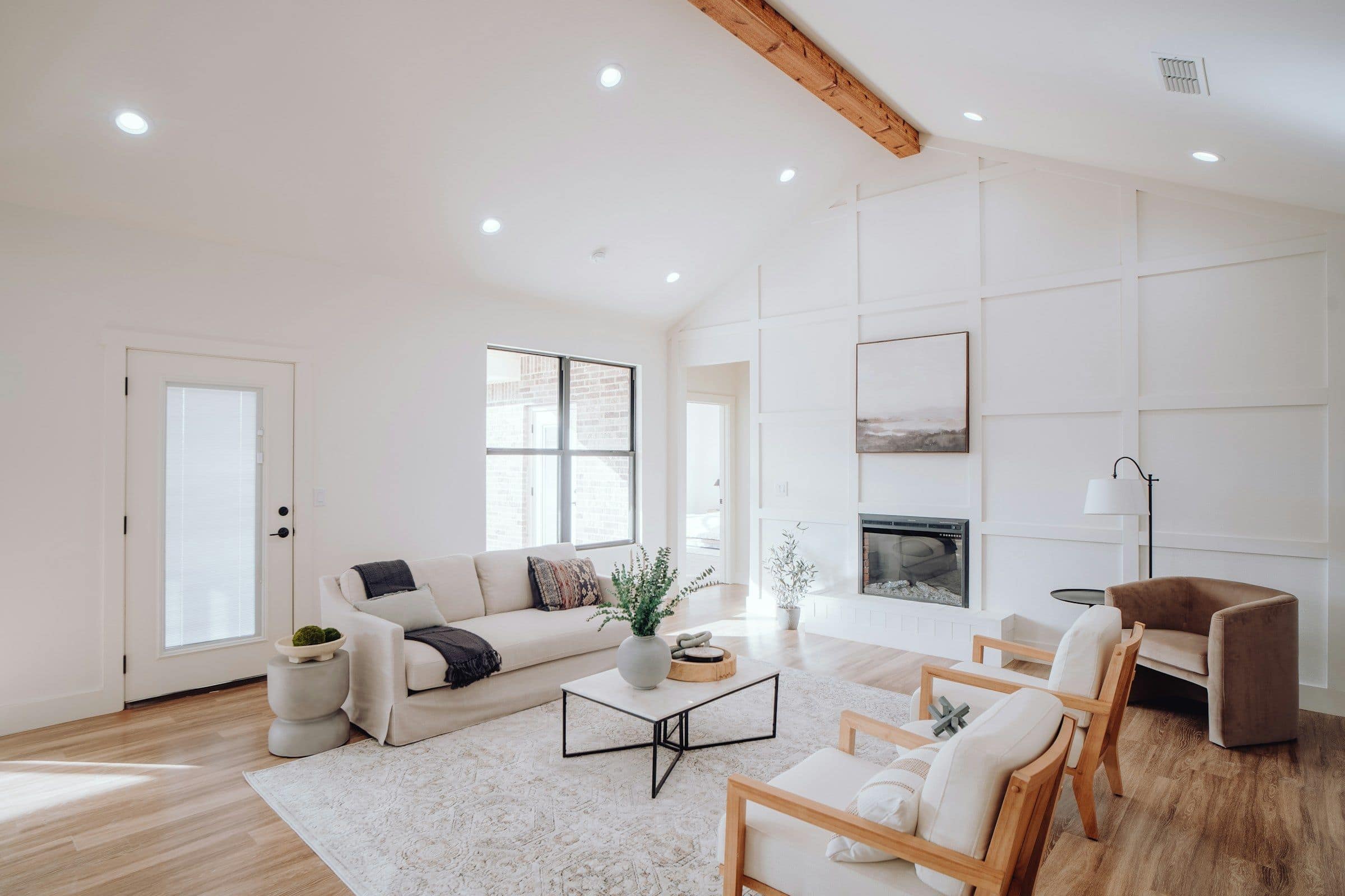 A bright, finished living room with a fireplace, sofa and lounge chairs