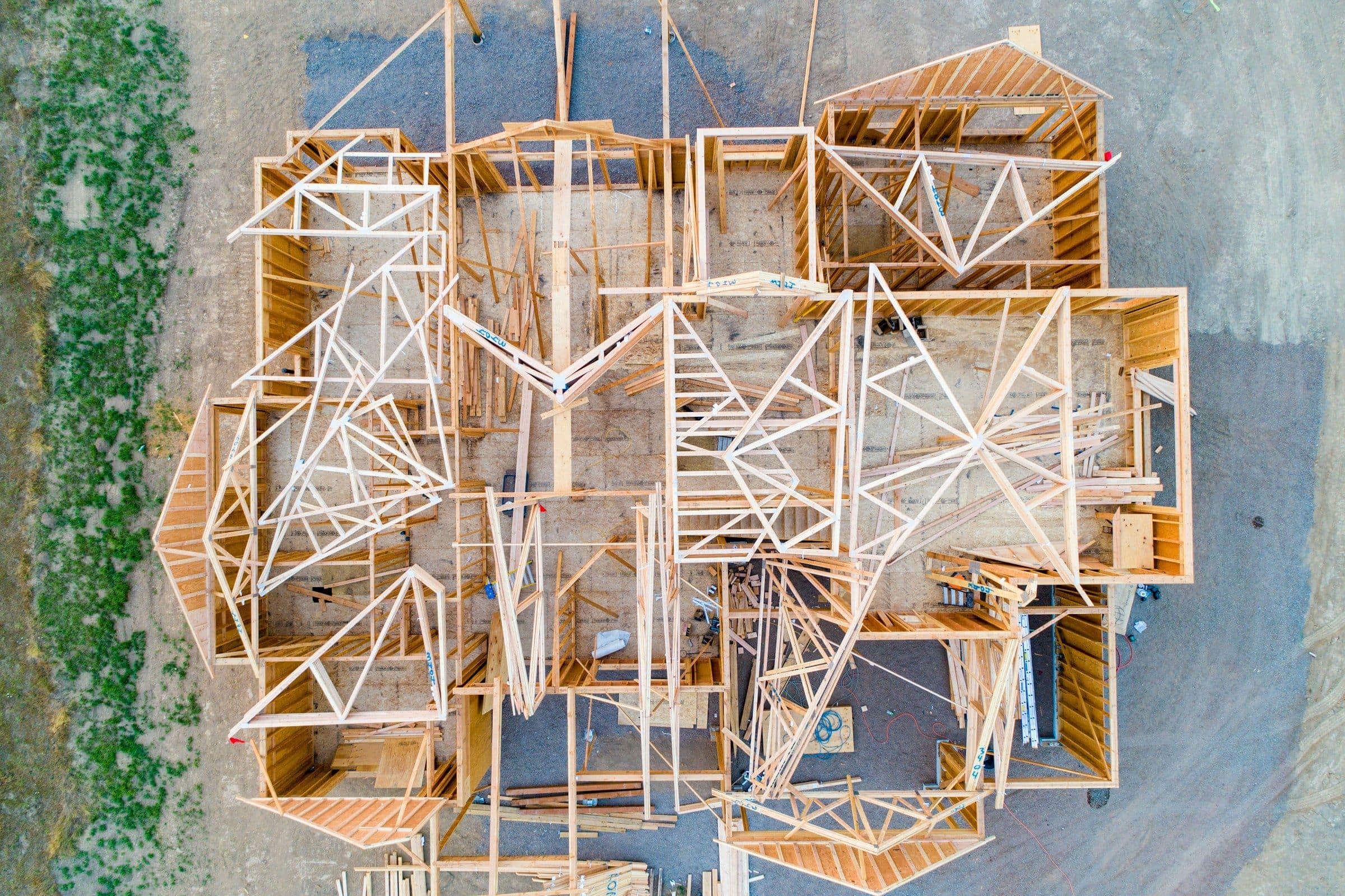 A house under construction seen from above, its timber framing and trusses exposed