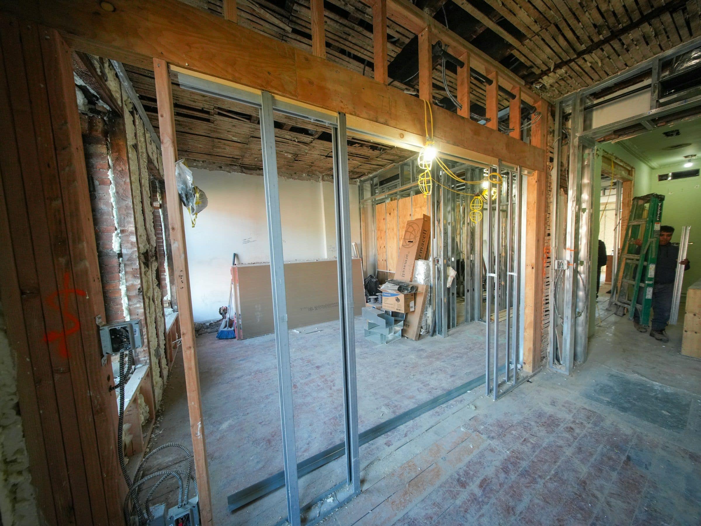 A gutted interior under renovation, with exposed brick, framing and new steel studs